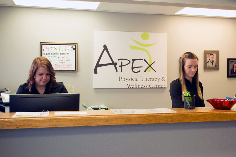 Two receptionists busy at work behind the front desk of Apex Physical Therapy & Wellness Center in Jamestown.