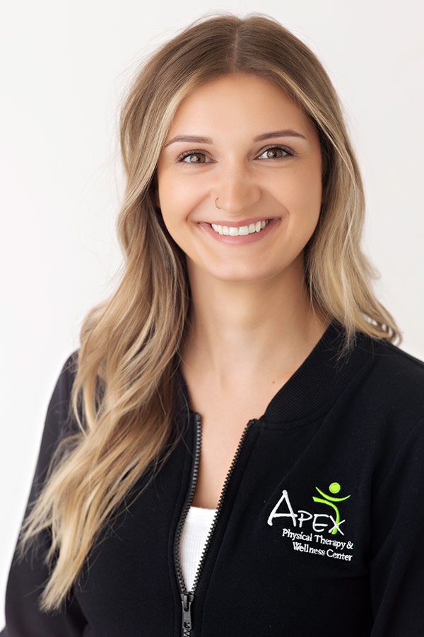 Confident and friendly professional woman in a branded wellness center uniform smiling for a portrait by Jonathan Tinklenberg.